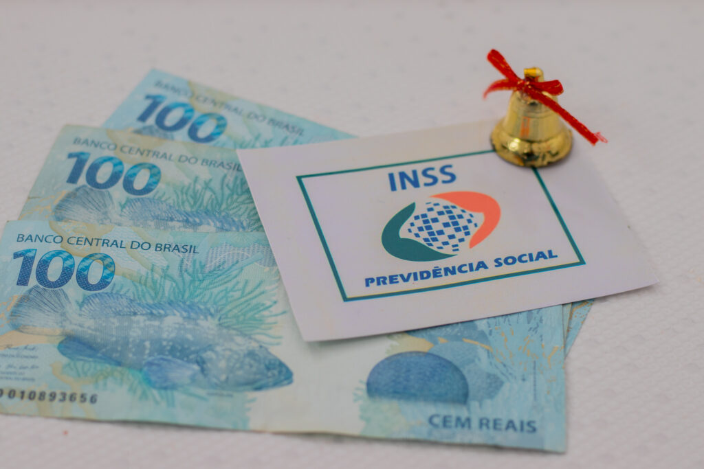 Notas de dinheiro em mesa, com logo do INSS ao lado.